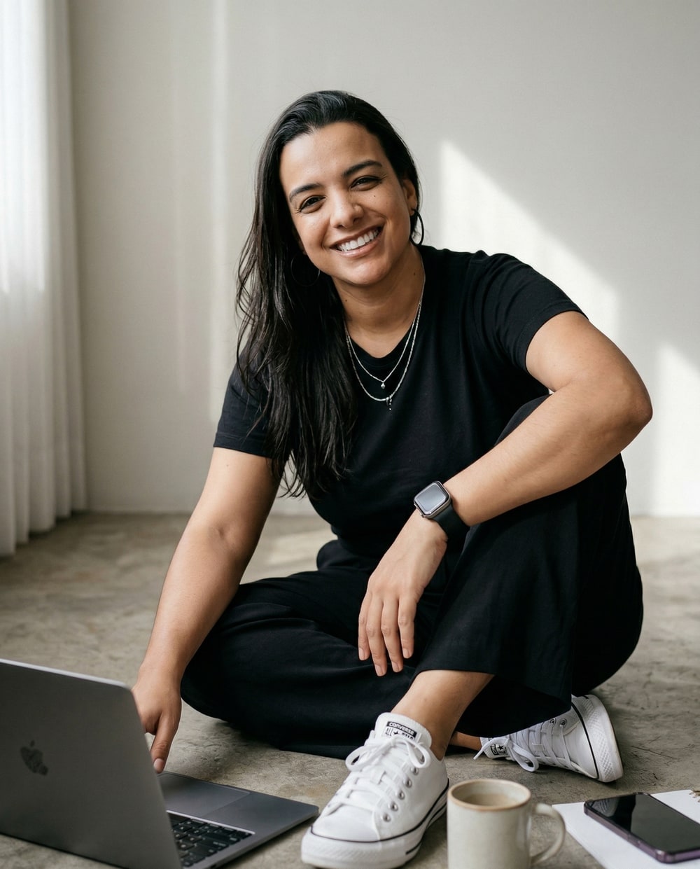 Camila Souza sorrindo, sentada ao lado de seu computador